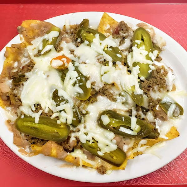 A plate of Luna's Mexican Rotisserie nachos with melted cheese, ground beef, and pickled jalapeños.